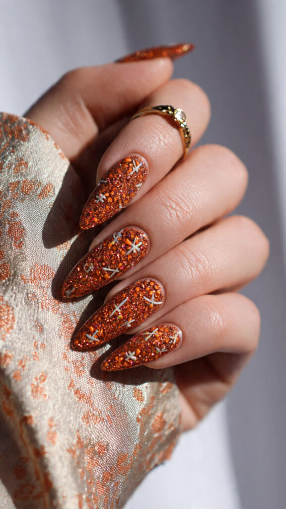 burnt orange glitter nails with stitched scarecrow
