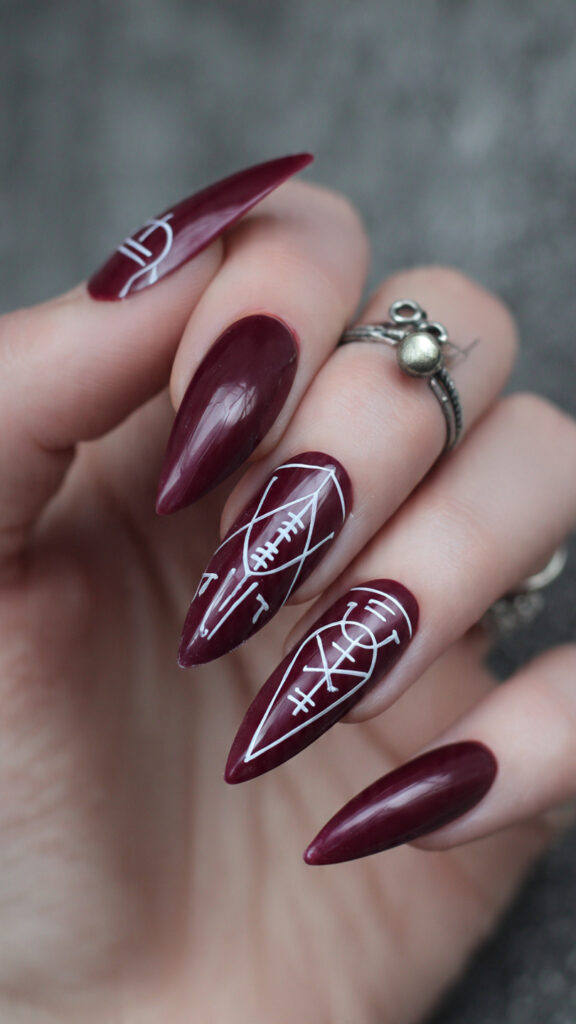 deep maroon stiletto nails with white rune